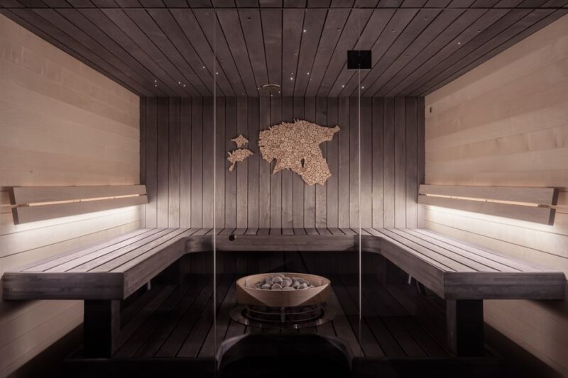 Luxurious wooden sauna interior with benches and a central stone feature, providing a calming ambiance.