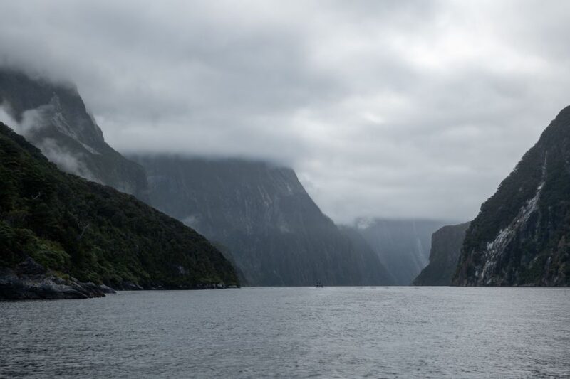 Dramatic view of Milford Sound with misty mountains and tranquil waters in New Zealand.