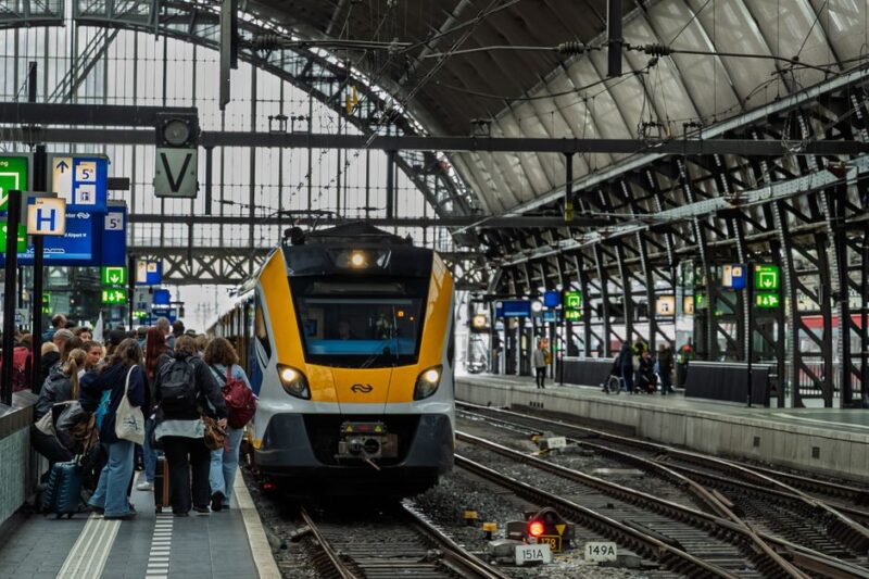 Crowded platform at Amsterdam Central Station with train arriving, capturing daily urban commute scene.